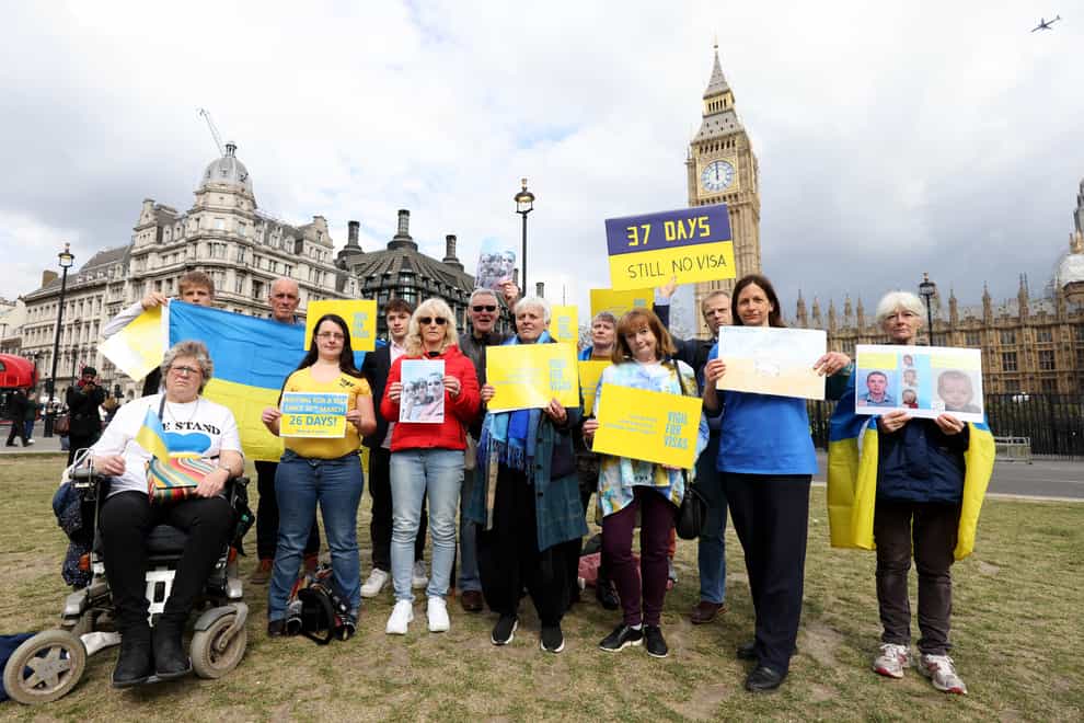 Protesters holding Ukrainian flags and banners as they attend a Vigil for Visas protest outside the Houses of Parliament, central London (James Manning/PA)