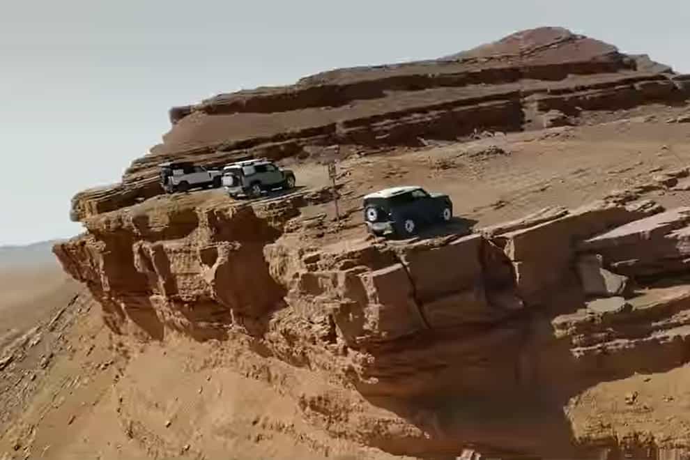 A scene from the Land Rover ad showing the vehicles parking on a cliff edge. (Jaguar Land Rover/PA)
