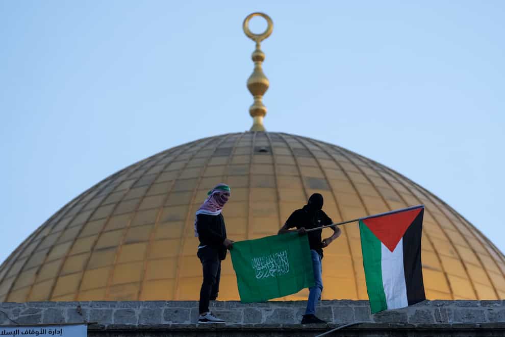 Masked Palestinians carry Palestinian and Hamas flags during Eid al-Fitr celebrations next to the next to the Dome of the Rock Mosque in the Al-Aqsa Mosque compound in the Old City of Jerusalem on Monday May 2 2022 (Mahmoud Illean/AP)