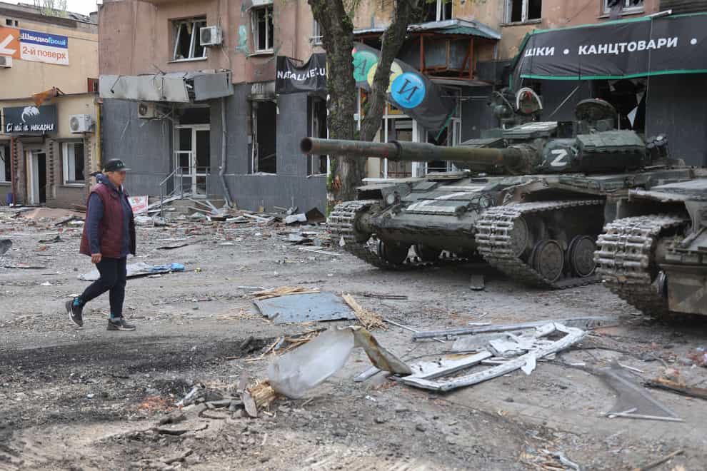 A woman walks past tanks of the Donetsk People’s Republic militia in Mariupol, in territory under the government of the Donetsk People’s Republic, eastern Ukraine (Alexei Alexandrov/AP)
