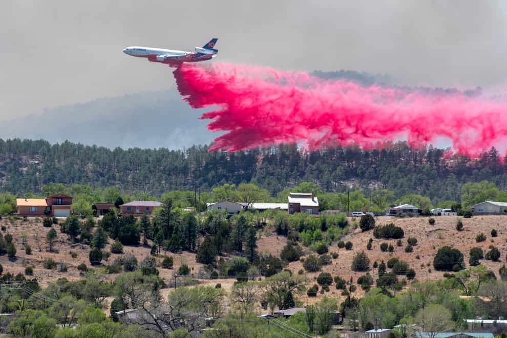 A slurry bomber dumps the fire retardant between the Calf Canyon/Hermit Peak Fire and homes on the westside of Las Vegas, New Mexico (The Albuquerque Journal via AP)