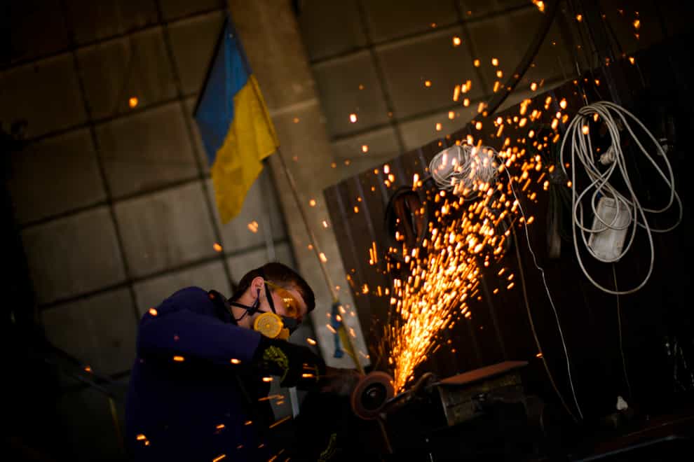 A volunteer shapes metal plates with an angle grinder at a facility producing material for Ukrainian soldiers in Zaporizhzhia, Ukraine (Francisco Seco/AP)