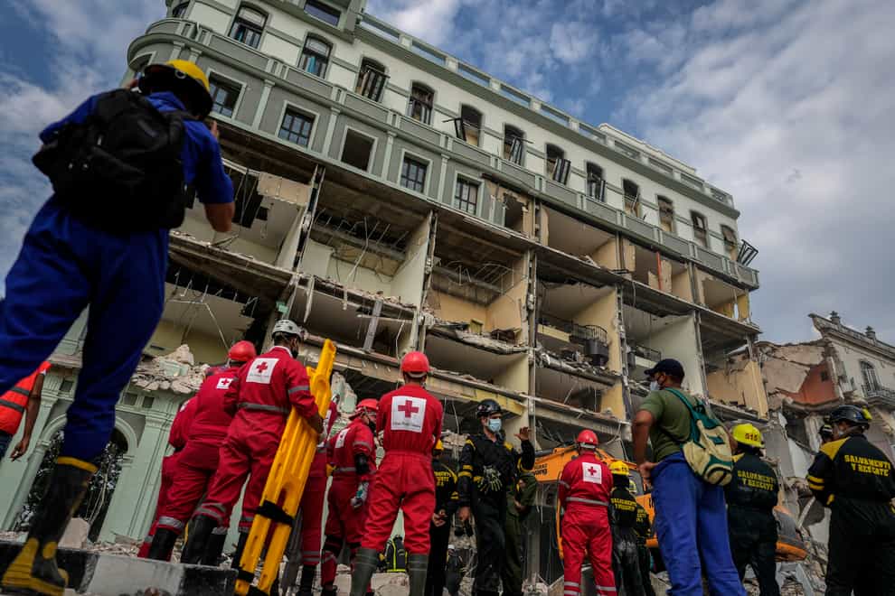 Red Cross and rescue teams wait to enter the site of a deadly explosion that destroyed the five-star Hotel Saratoga, in Havana, Cuba, Friday, May 6, 2022. A powerful explosion apparently caused by a natural gas leak killed at least 18 people, including a pregnant woman and a child, and injured dozens Friday when it blew away outer walls from the luxury hotel in the heart of Cuba’s capital. (AP Photo/Ramon Espinosa)