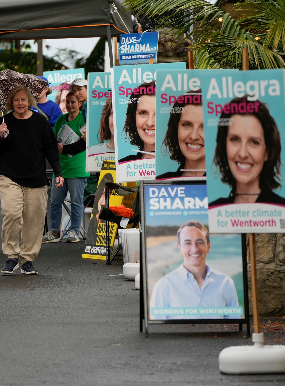 A woman walks past billboards for candidates outside a polling station in Sydney (AP)