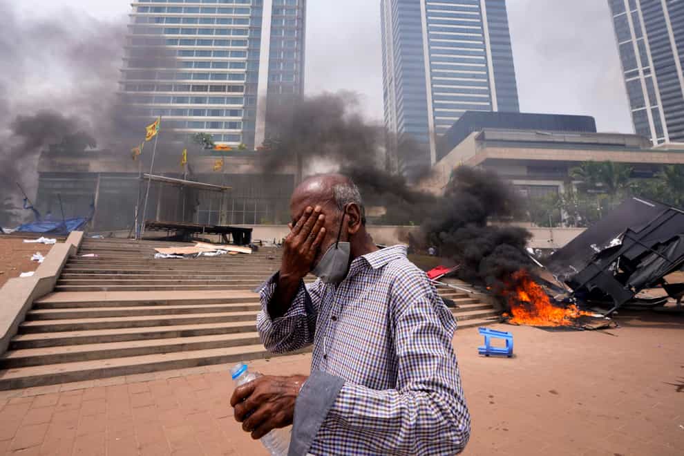 A Sri Lankan man reacts to tear gas as he walks past the vandalised site of anti-government protests outside the President’s office in Colombo, Sri Lanka, on Monday May 9 2022 (Eranga Jayawardena/AP)