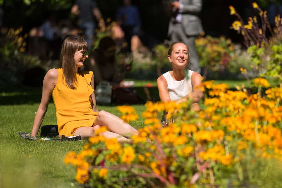 Two women sit in the sun in Whitehall Gardens, Westminster (Dominic Lipinski/PA)