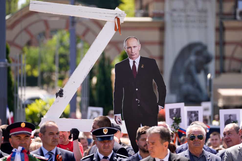 People hold a picture of Russian President Vladimir Putin and a letter Z during the Victory Day ceremony in Belgrade, Serbia, on Monday May 9 2022 (Darko Vojinovic/AP)