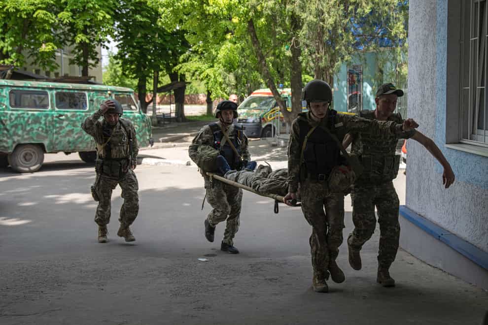 Ukrainian servicemen carry an injured comrade on a stretcher after an attack by Russian forces in the Donetsk region, Ukraine, on Monday May 9 2022 (Evgeniy Maloletka/AP)