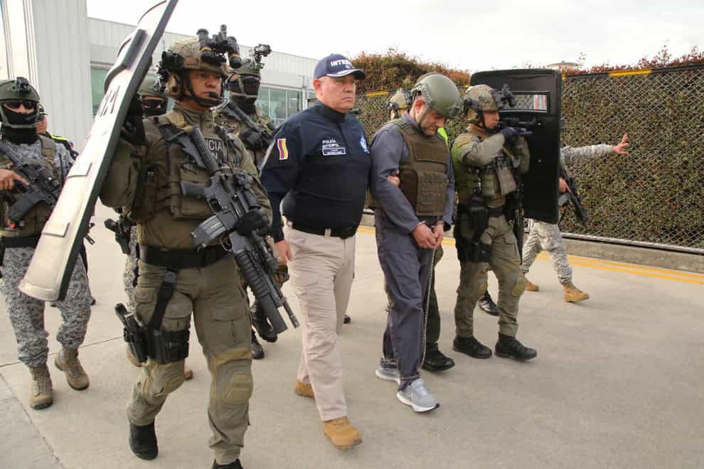 Police escort Dairo Antonio Usuga, centre, also known as Otoniel, leader of the violent Clan del Golfo cartel, prior to his extradition to the US (Colombian presidential press office/AP)