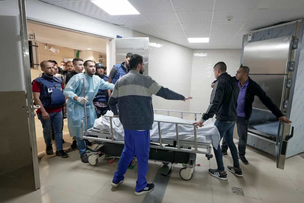 Journalists and medics wheel the body of Shireen Abu Akleh, a journalist for Al-Jazeera, into a morgue at a hospital in the West Bank town of Jenin on Wednesday May 11 2022 (Majdi Mohammed/AP)