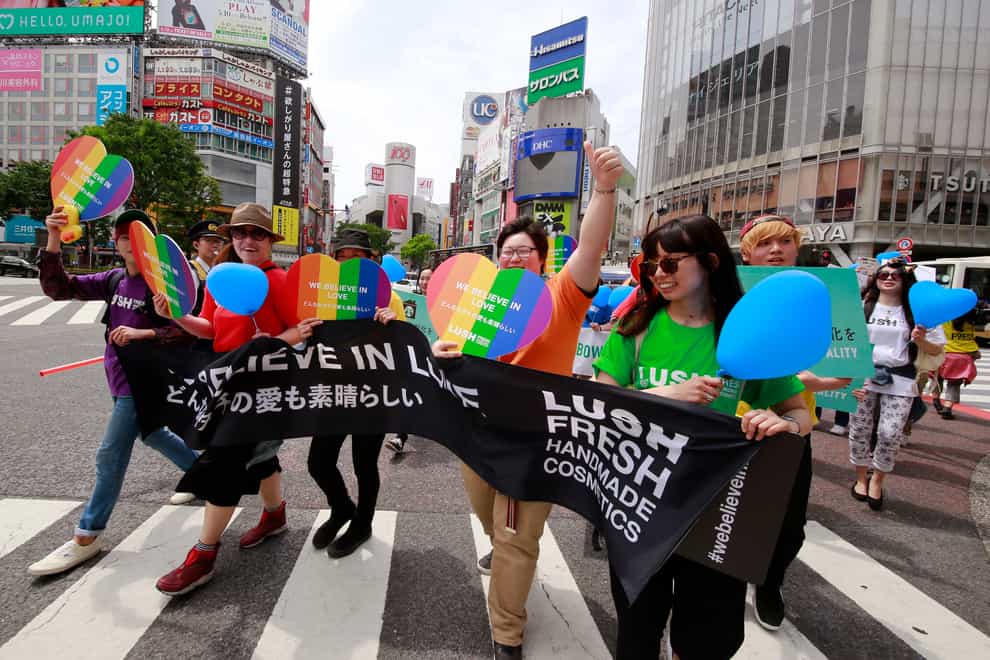 People march with rainbow-coloured and heart-shaped posters and a banner during the Tokyo Rainbow Pride parade in Tokyo’s Shibuya district in 2017 (Shizuo Kambayashi/AP)