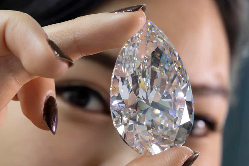 A Christie’s employee holds “The Rock” a white diamond of 228,31 carats who is the largest white diamond ever seen throughout auction market history, during a preview at Christie’s, in Geneva, Switzerland, Friday, May 6, 2022. The Rock is estimated between 19,000,000 – 30,000,000 CHF (Swiss Francs) will sold as hightlight of the Geneva Magnificent Jewels auction on 11 May 2022. (Salvatore Di Nolfi/Keystone via AP)