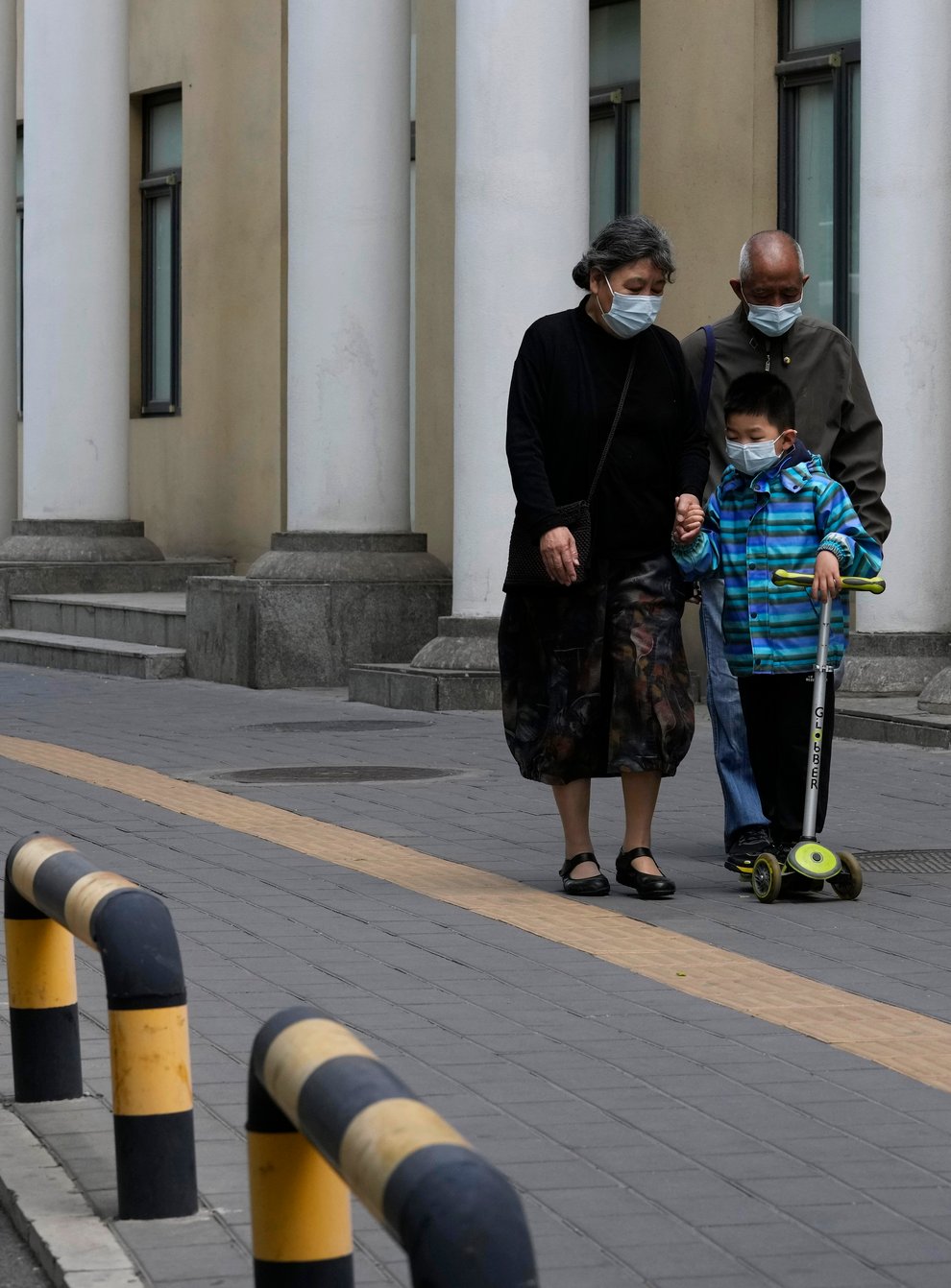Residents wearing masks walk along a quiet street in Beijing (AP)