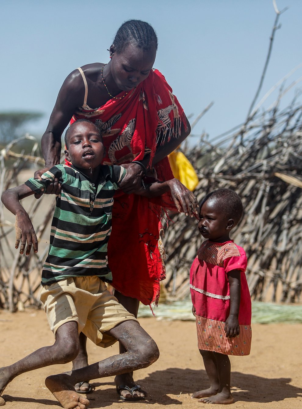 A mother helps her malnourished son stand after he collapsed near their hut in the village of Lomoputh in northern Kenya on Thursday May 12 2022 (Brian Inganga/AP)