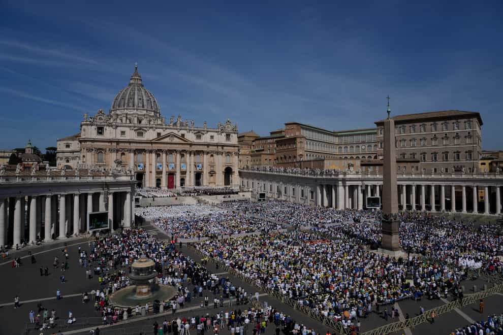 The tapestries depicting the 10 new saints hang over a packed St Peter’s Square (Gregorio Borgia/AP)