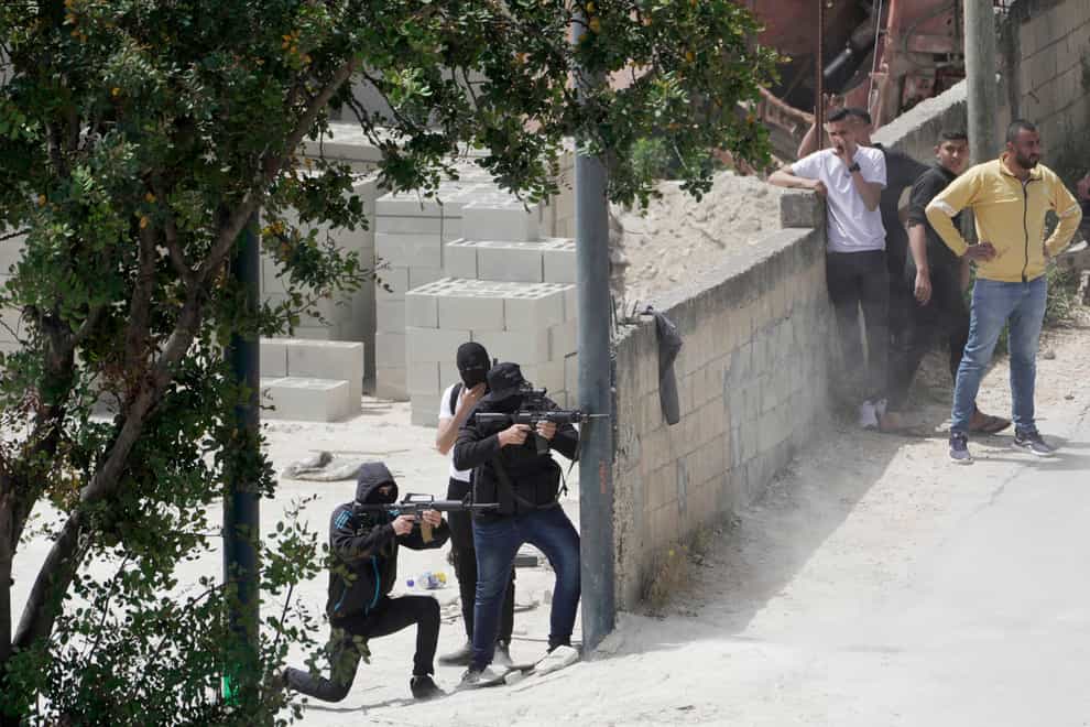 Palestinian gunmen take aim during an Israeli military operation in the West Bank town of Jenin, Friday, May 13, 2022 (Majdi Mohammed/AP)