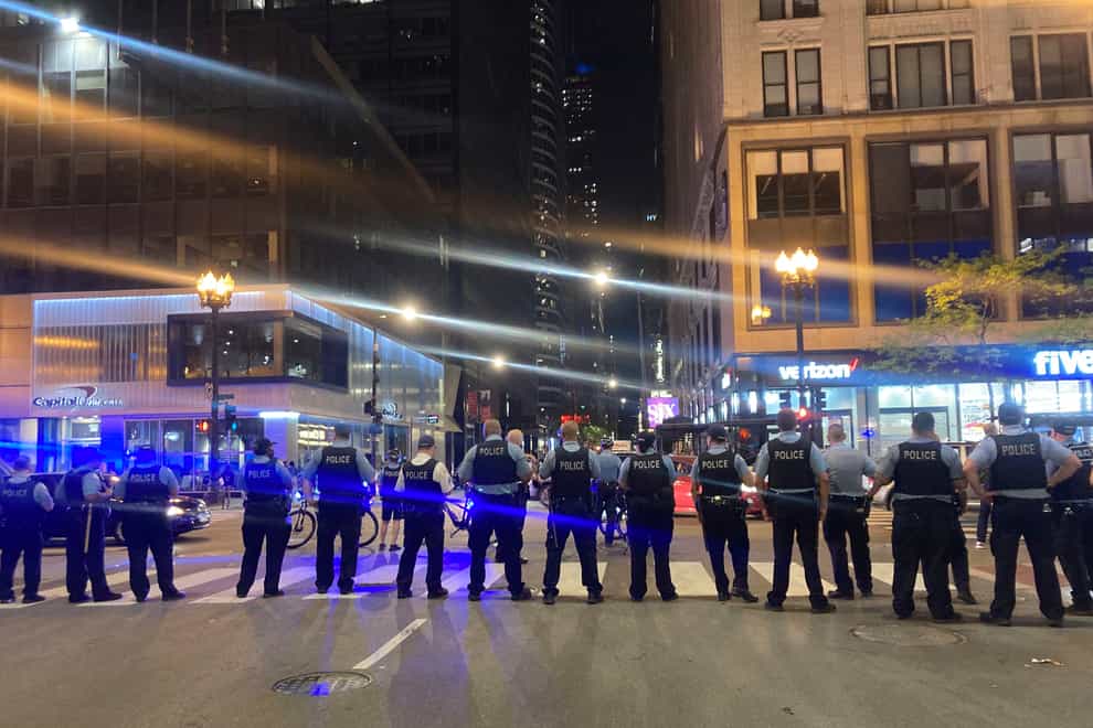 Chicago police block traffic near State and Monroe streets after crowds of young people flooded the Loop after a fatal shooting in Millennial Park in Chicago (Tina Sfondeles/Chicago Sun-Times via AP)