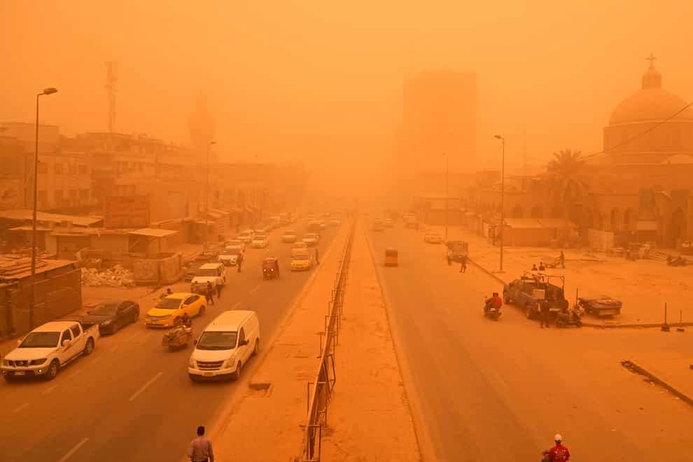 People navigate a street during a sandstorm in Baghdad, Iraq (Hadi Mizban/AP)