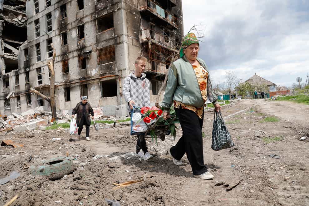 Women walk past a destroyed building in Mariupol (Alexei Alexandrov/AP)