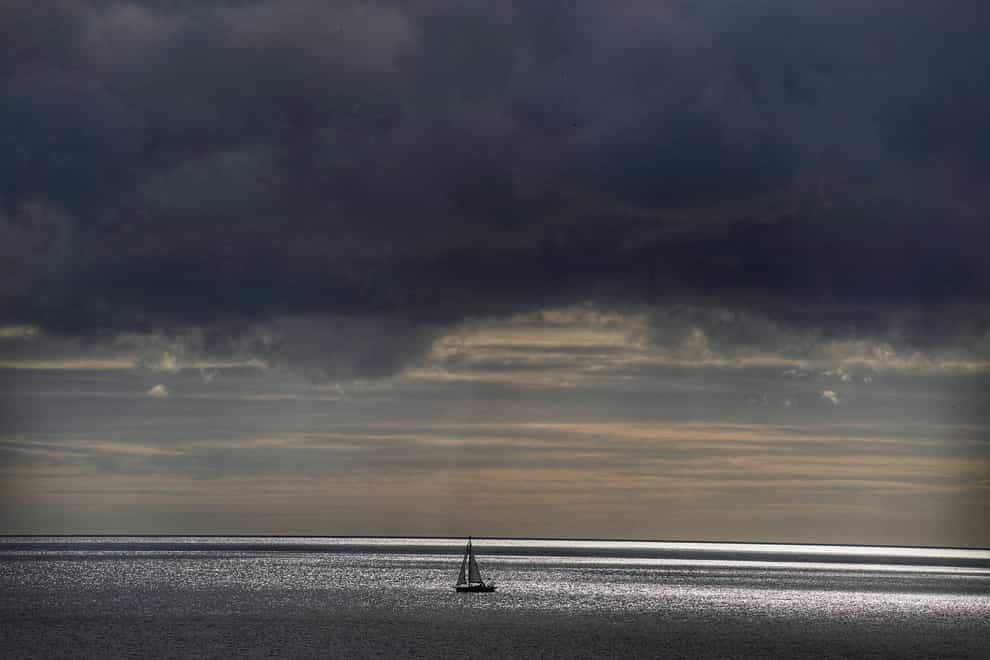 A yacht sails across the North Sea under storm clouds (Owen Humphreys/PA)