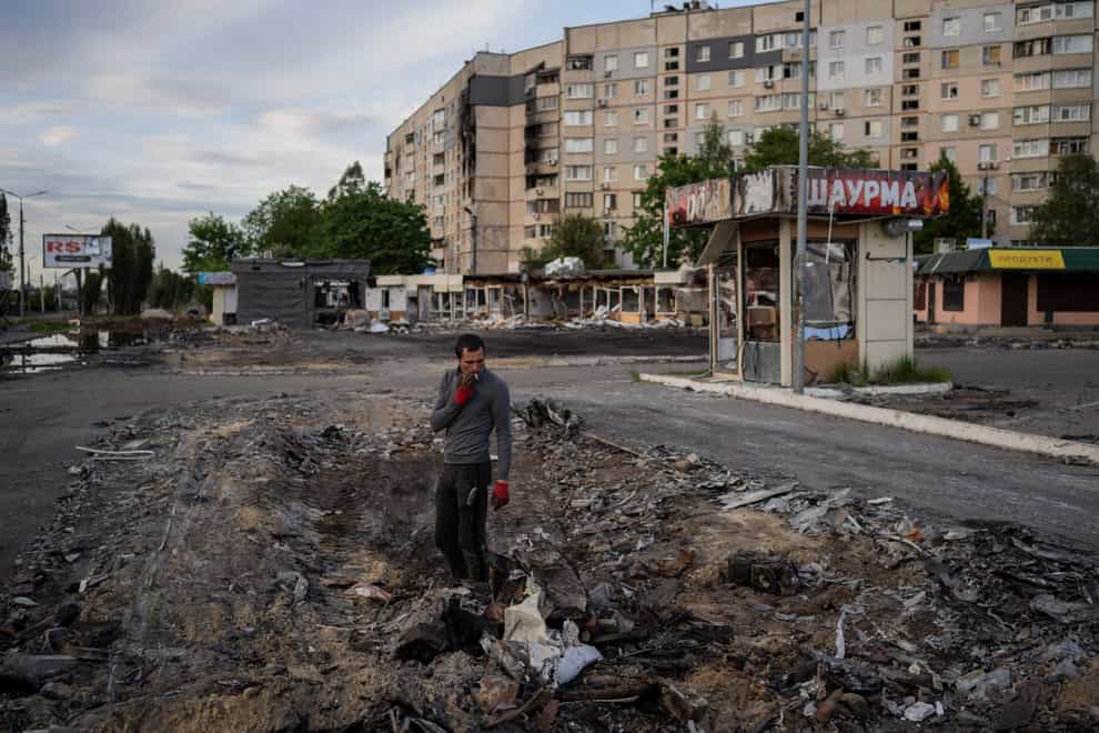 A man searches for metal scraps in a bombed-out neighbourhood in Kharkiv, eastern Ukraine (AP)