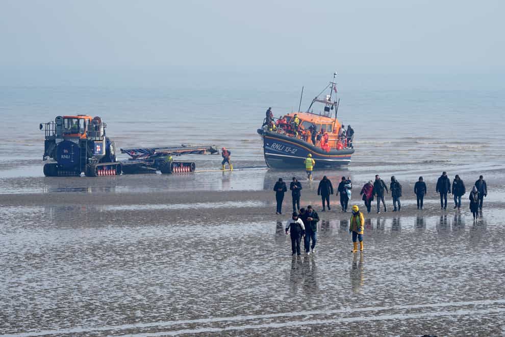 A group of people thought to be migrants are guided up the beach after being brought in to Dungeness, Kent (GaretH Fuller/PA)