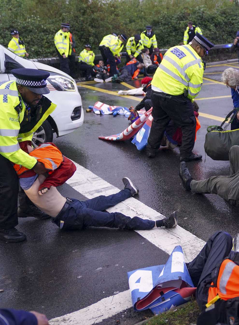 Police officers detain a protester occupying a roundabout near the M25 (PA)