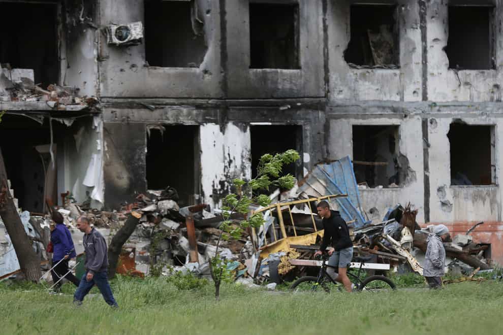 People walk past a destroyed building in Mariupol (Alexei Alexandrov/AP)