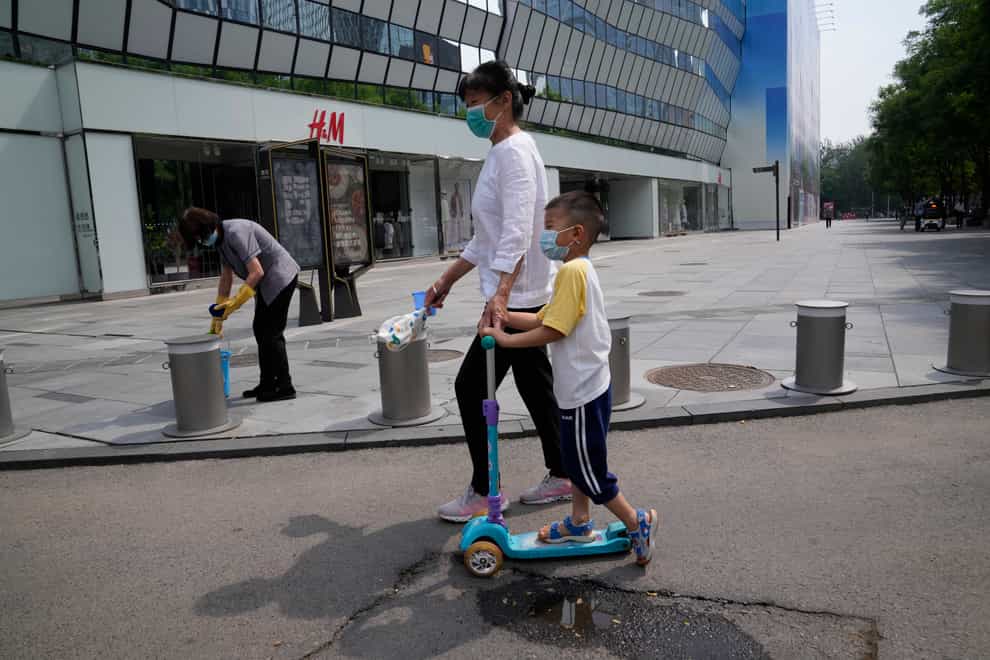 Residents pass by a quiet shopping centre area in Beijing (Ng Han Guan/AP)