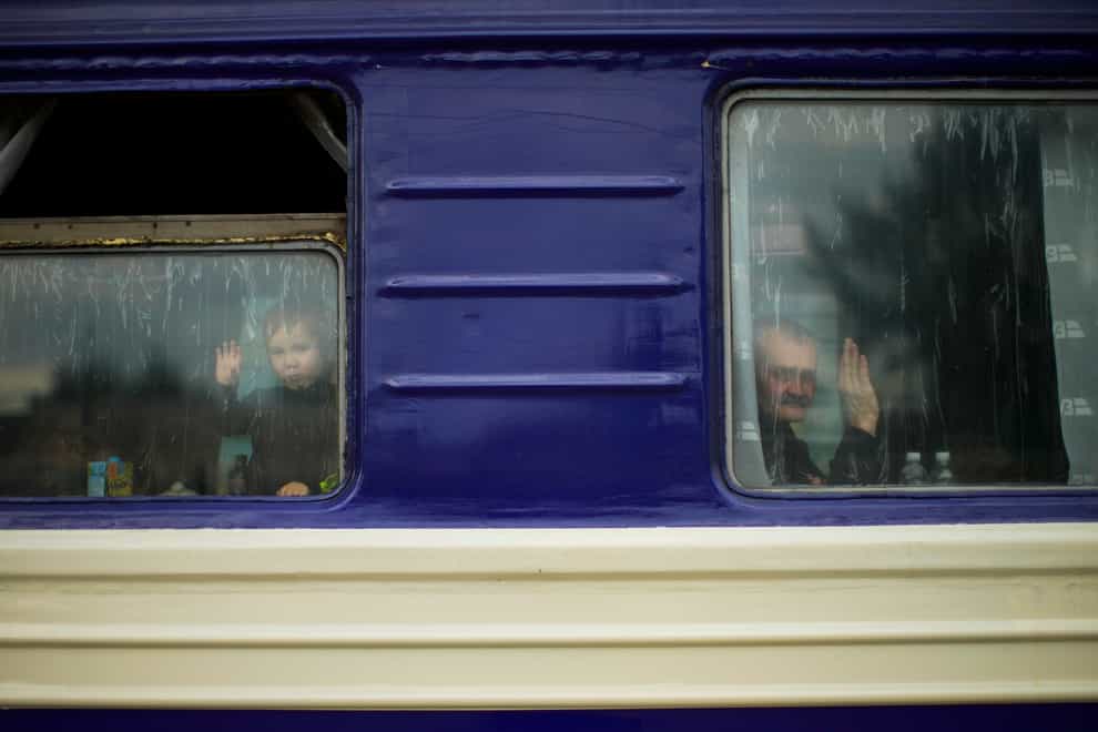A child and a man, fleeing from heavy shelling, wave to a photographer before departing in an evacuation train at Pokrovsk train station (Francisco Seco/AP)