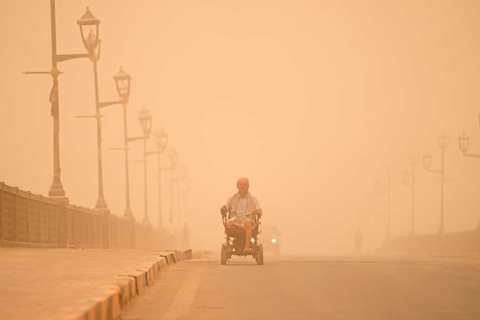 A man navigates his wheelchair on a street during a sand storm in Baghdad, Iraq, on Monday May 23 2022 (Hadi Mizban/AP)