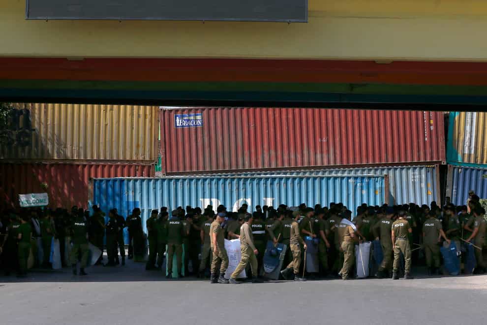 Police officers assemble next to shipping containers placed by authorities block a road leading to capital city in an attempt to foil the planned rally (AP)