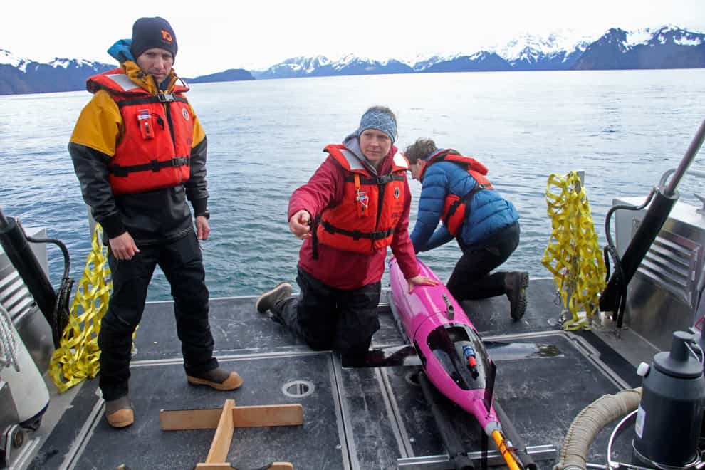 Oceanographers Andrew McDonnell, left, and Claudine Hauri, middle, are pictured with engineer Joran Kemme after an underwater glider is pulled aboard the University of Alaska Fairbanks research vessel Nanuq from the Gulf of Alaska (Mark Thiessen/AP)