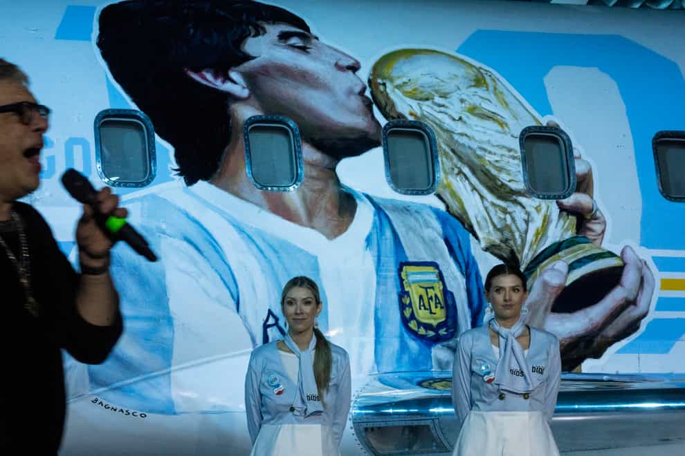 Flight attendants stand by as rock singer Juanse performs during the presentation of an aircraft dedicated to the late Diego Maradona (Rodrigo Abd/AP)