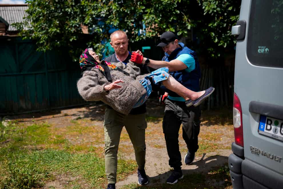 A woman is carried from her home by volunteers in Bakhmut, eastern Ukraine (Francisco Seco/AP)