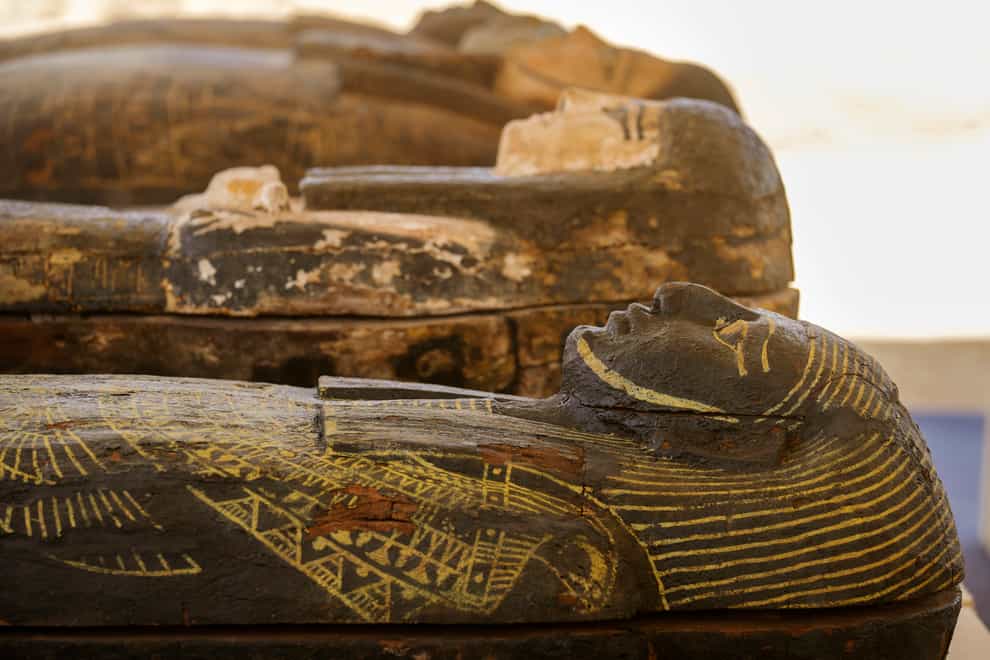 Painted coffins with well-preserved mummies inside, dating back to the Late Period of ancient Egypt around 500BC, are displayed at a makeshift exhibit at the feet of the Step Pyramid of Djoser in Saqqara, 15 miles southwest of Cairo, Egypt, on Monday May 30 2022 (Amr Nabil/AP)