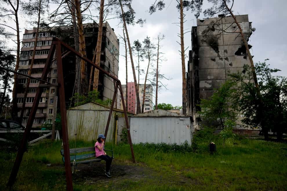 A girl sits on a swing outside destroyed buildings in Irpin, Ukraine (Natacha Pisarenko/AP)
