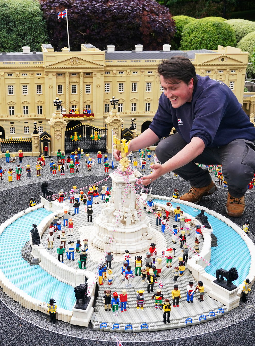 A member of the Legoland Windsor staff makes adjustments to a Lego replica of the Queen Victoria Memorial (Jonathan Brady/PA)