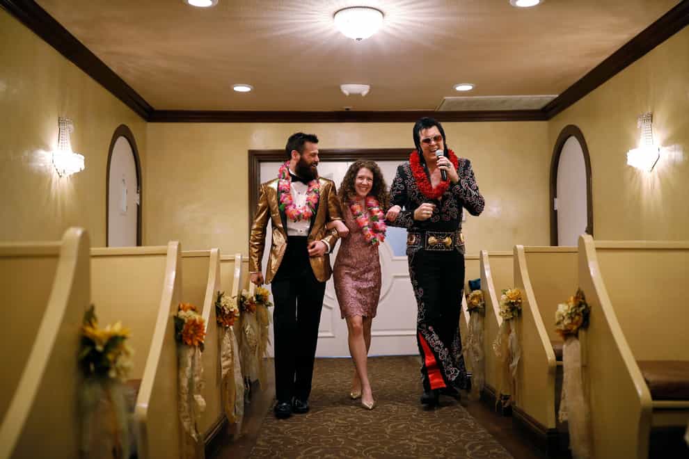 Elvis impersonator Brendan Paul, right, walks down the aisle during a wedding ceremony for Katie Salvatore, centre, and Eric Wheeler at the Graceland Wedding Chapel in Las Vegas (John Locher/AP)