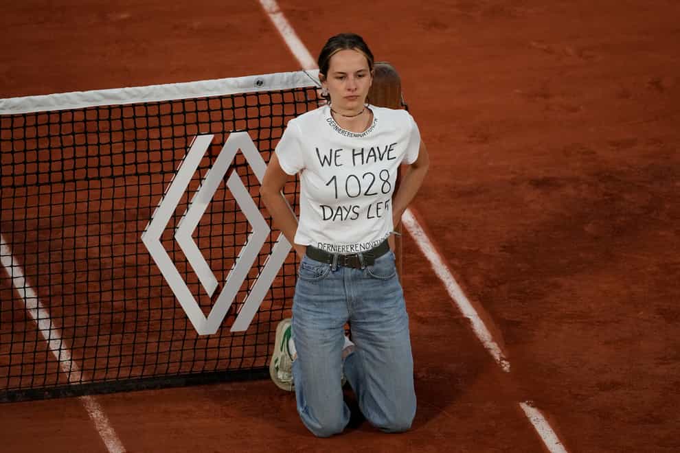 A climate activist ties herself to the net during the semi-final match between Marin Cilic and Casper Ruud (Thibault Camus/AP)