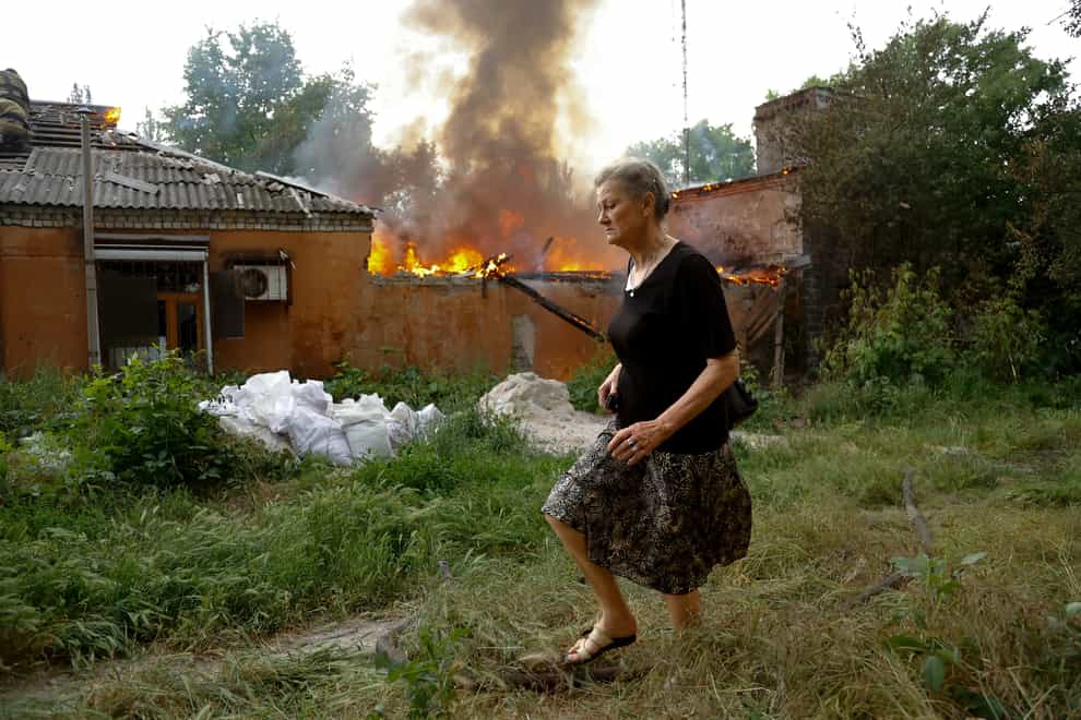 A woman runs from a house that’s on fire after shelling in Donetsk, on the territory which is under the Government of the Donetsk People’s Republic control, eastern Ukraine (Alexei Alexandrov/AP)
