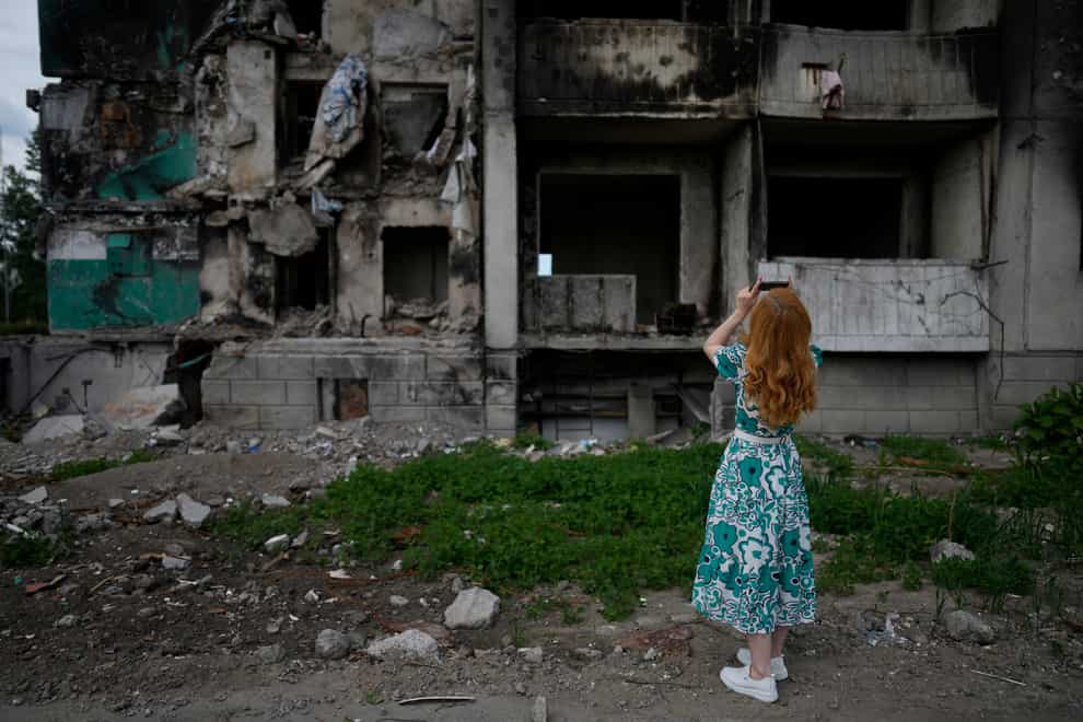 A woman takes pictures of a building destroyed by shelling, in Borodyanka, on the outskirts of Kyiv (Natacha Pisarenko/AP)