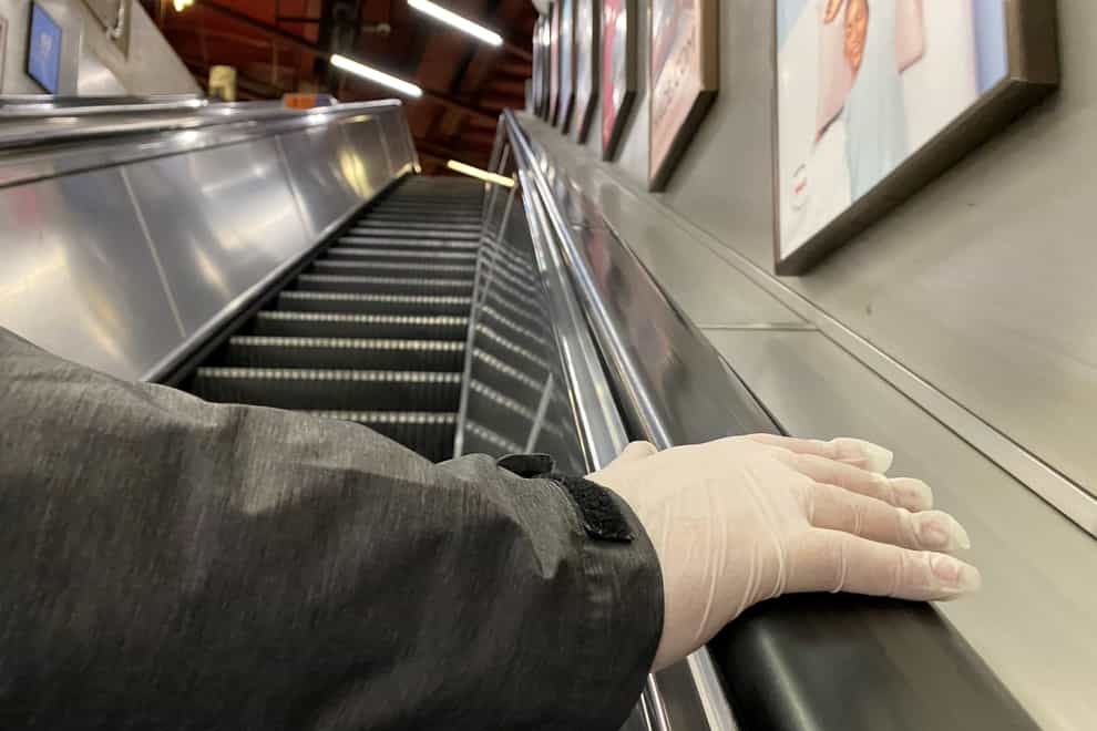 A person with a gloved hand uses an escalator in Baker Street Underground Station in London (Luciana Guerra/PA)