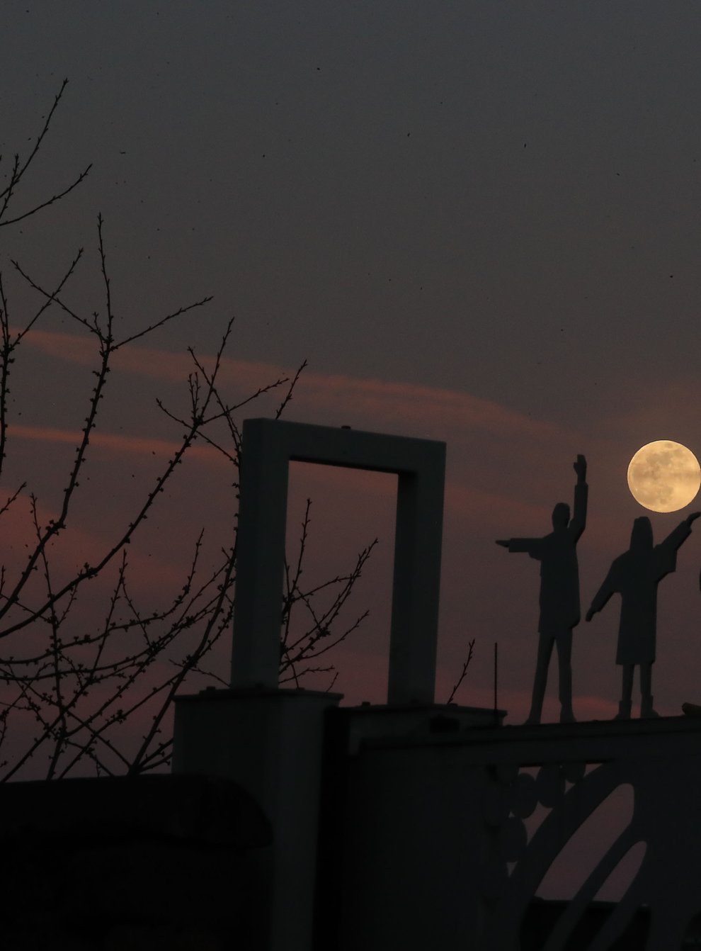 The moon rises behind a statue of the Beatles on Penny Lane in Liverpool (Peter Byrne/PA)