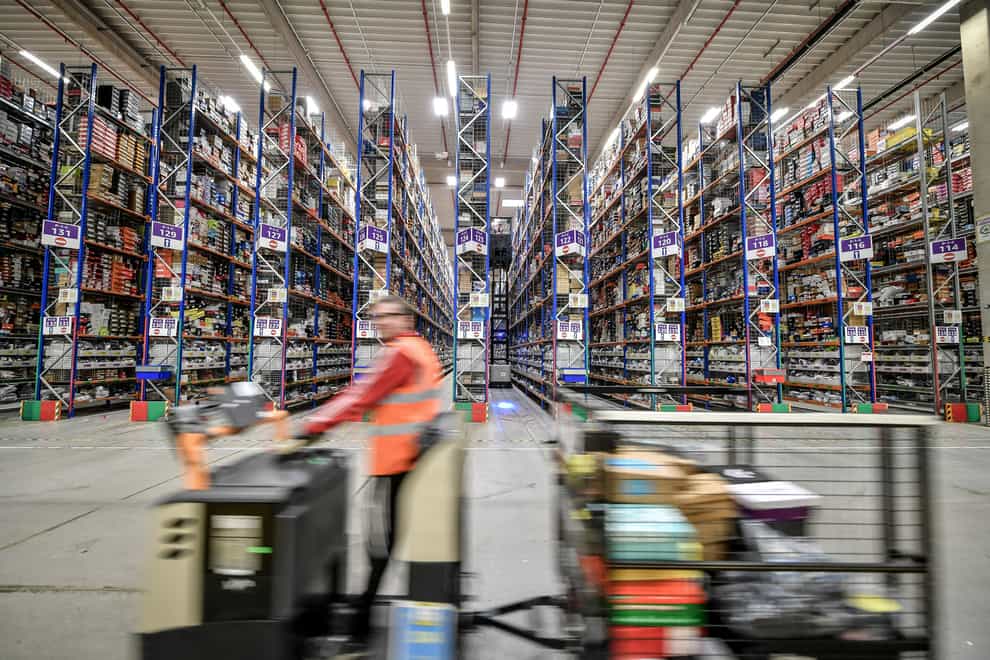 A worker on a motorised trolley passes thousands of items on high level racking at Amazon’s fulfilment centre in Swansea (Ben Birchall/PA)