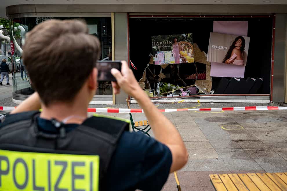 A policeman takes a photo of the damaged storefront at the scene of the fatal crash in Berlin (Fabian Sommer/dpa via AP)