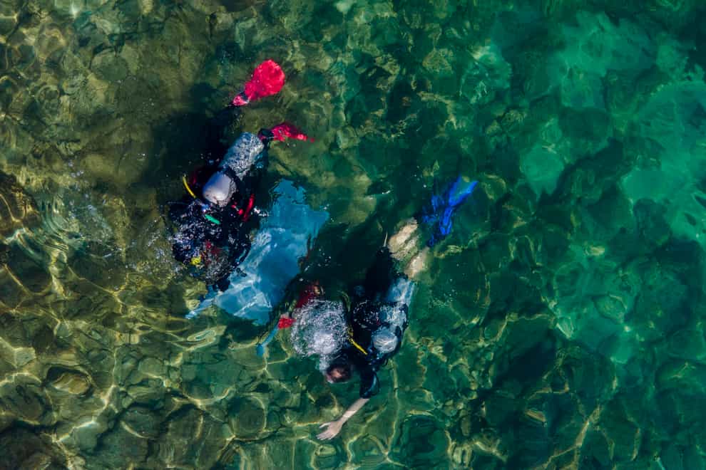 Scuba-diving volunteers collect rubbish during the World Ocean Day event (Ariel Schalit/AP)