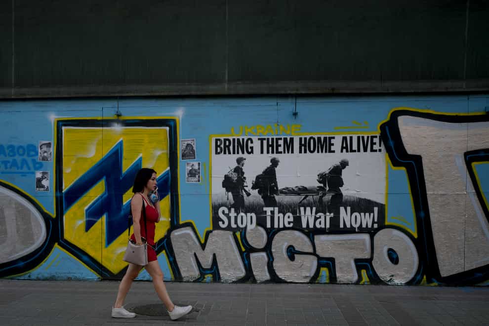 A woman walks in front of an anti-war poster in Kyiv, Ukraine (Natacha Pisarenko/AP)