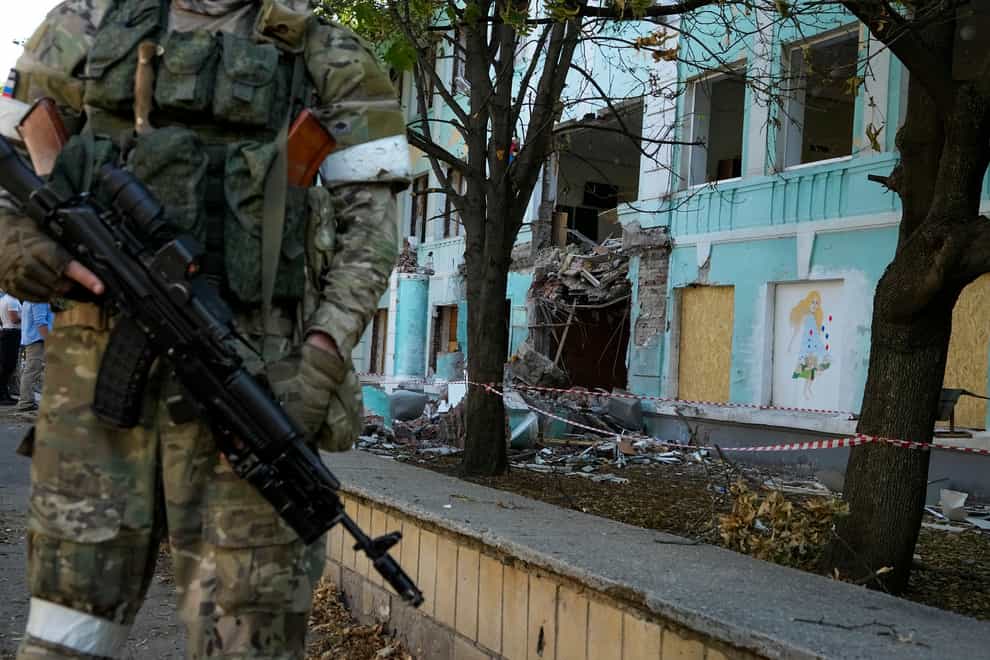 A Russian soldier stands next to a damaged by shelling school-building in Donetsk, on the territory which is under the Government of the Donetsk People’s Republic control, eastern Ukraine, Monday, June 13, 2022. This photo was taken during a trip organized by the Russian Ministry of Defense. (AP Photo)