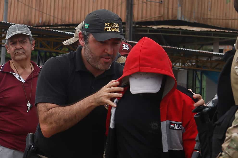 A federal police officer escorts a suspect (Edmar Barros/AP)
